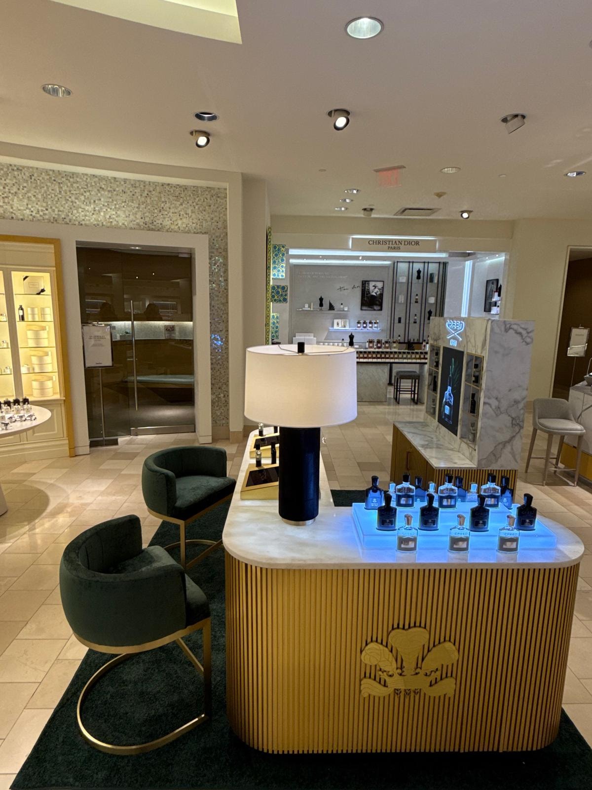 Creed fragrance bottles illuminated with blue LED lighting on marble counter