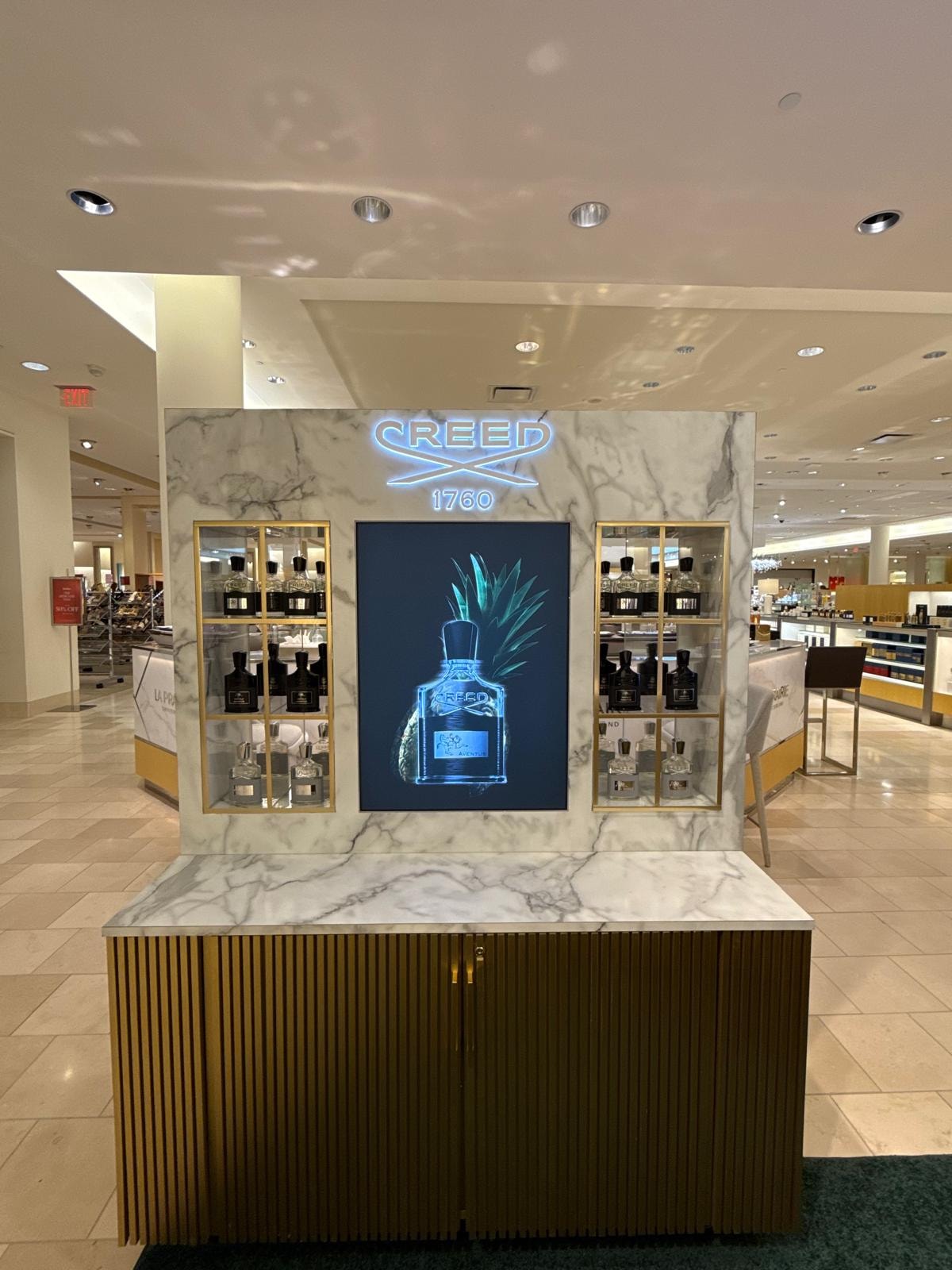 Closeup of Creed 1760 freestanding kiosk with neon signage and product shelving