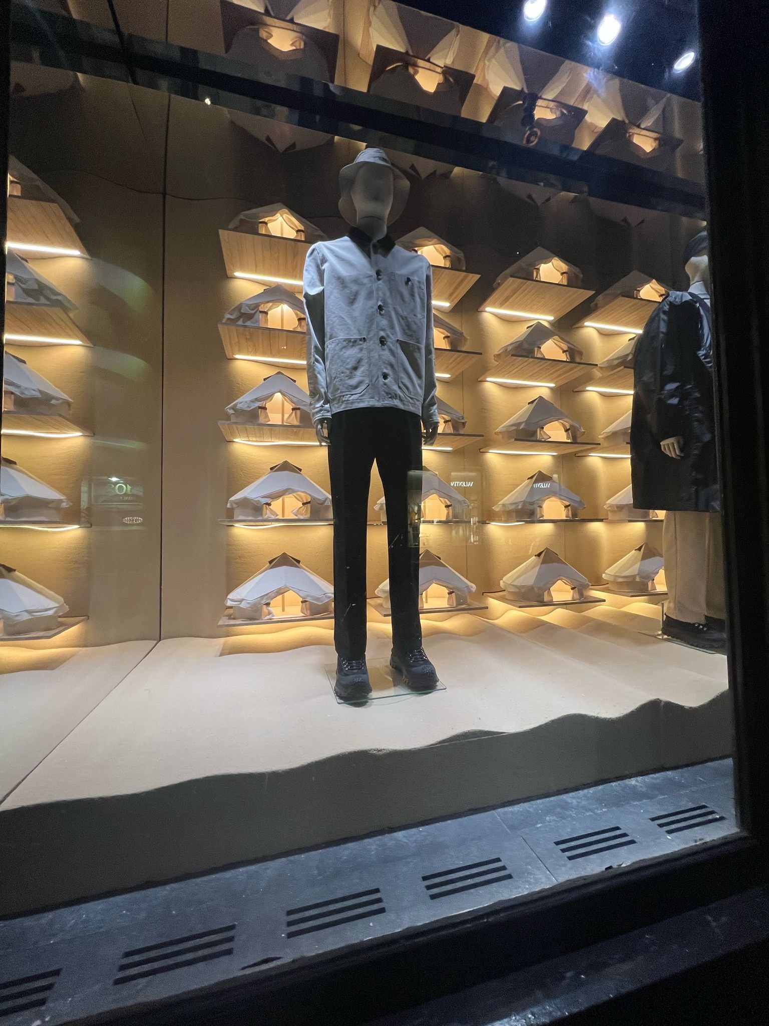Moncler window display mannequin with tent-shaped shelving and dimensional lettering